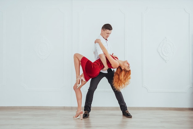 Mulher bonita nova em um vestido vermelho e uma dança do homem isolada em um fundo branco.