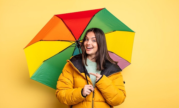 Mulher bonita olhando animado e surpreso apontando para o lado. conceito de inverno e guarda-chuva