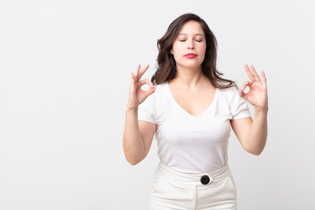 Mulher bonita olhando concentrada e meditando, sentindo-se satisfeita e relaxada, pensando ou fazendo uma escolha