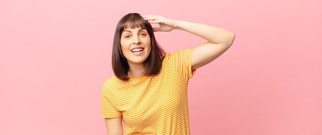 Mulher bonita parecendo feliz, atônita e surpresa, sorrindo e percebendo uma notícia incrível e incrível