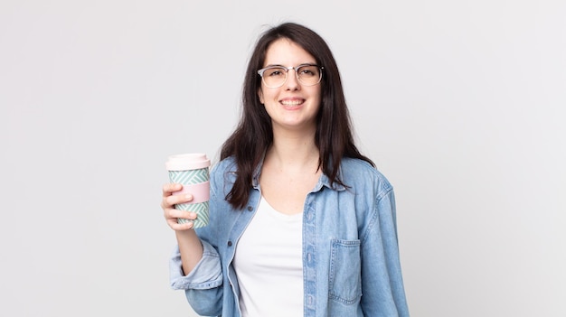 Mulher bonita parecendo feliz e agradavelmente surpresa segurando um café para viagem