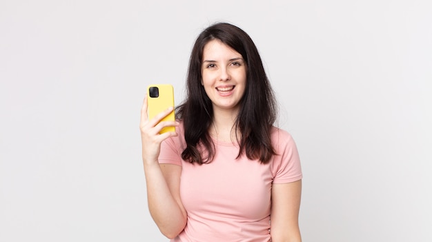 Mulher bonita parecendo feliz e agradavelmente surpresa usando um telefone inteligente