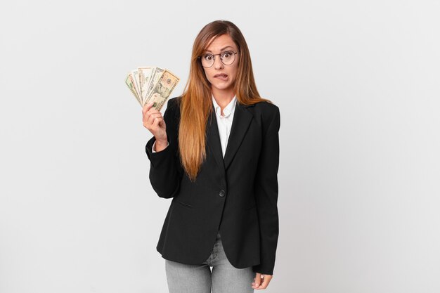 Mulher bonita parecendo perplexa e confusa. conceito de negócios e dólares