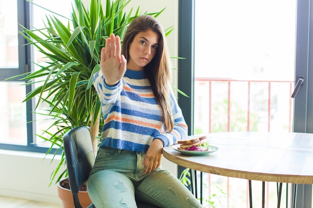 Mulher bonita parecendo séria, severa, descontente e irritada mostrando a palma da mão aberta fazendo gesto de pare