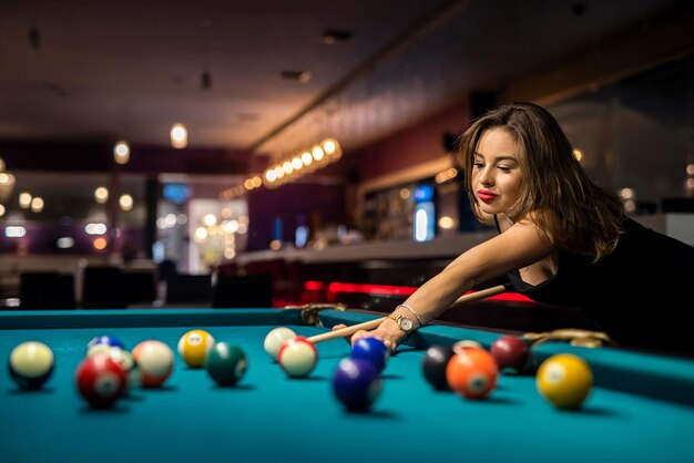 Mulher bonita passa o tempo livre jogando sinuca no pub