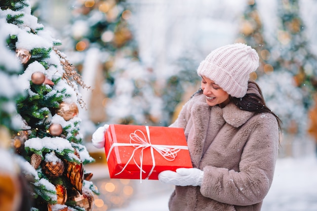 Mulher bonita perto da árvore de Natal na neve ao ar livre