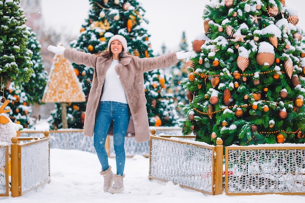 Mulher bonita perto da árvore de Natal na neve ao ar livre