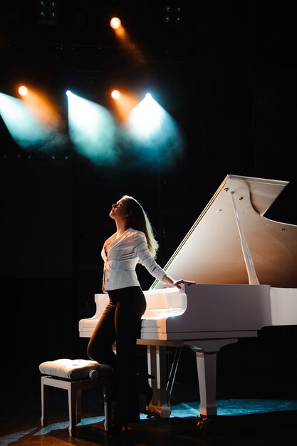 Mulher bonita perto de piano branco om a cena