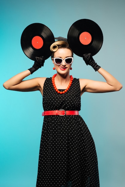 Mulher bonita pinup com penteado retrô e maquiagem posando com disco de vinil