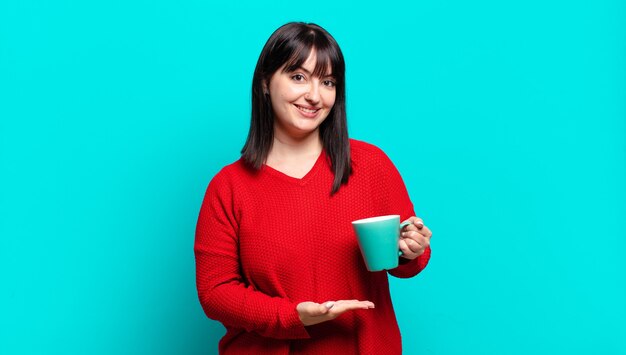 Mulher bonita plus size sorrindo alegremente, se sentindo feliz e mostrando um conceito no espaço da cópia com a palma da mão