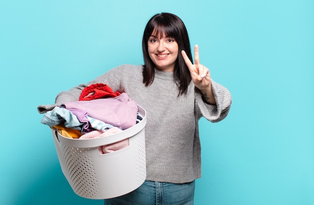 Mulher bonita plus size sorrindo e parecendo feliz, despreocupada e positiva, gesticulando vitória ou paz com uma mão