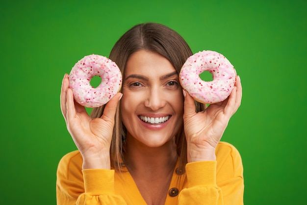 Foto mulher bonita posando com donuts sobre fundo verde