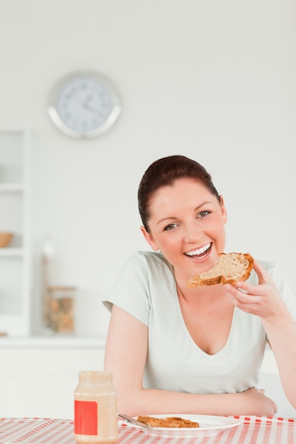 Mulher bonita que prepara uma fatia de pão e marmelada