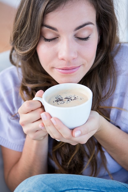 Mulher bonita que toma uma xícara de café