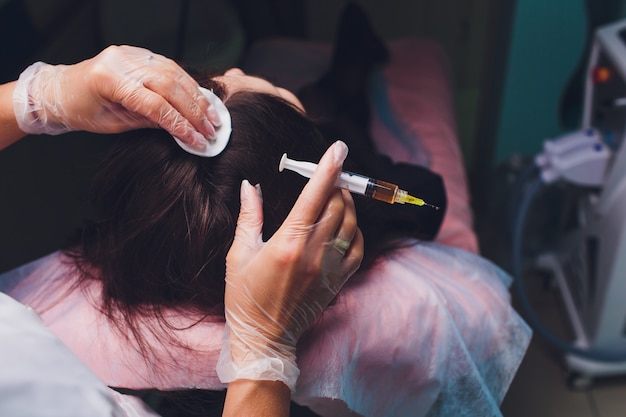 Mulher bonita, recebendo injeção para o crescimento do cabelo.