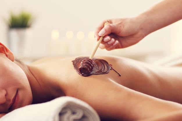 Mulher bonita recebendo massagem de chocolate no spa