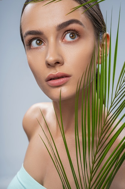 Mulher bonita relaxada com folha de palmeira verde