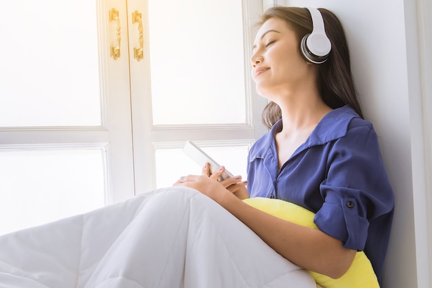 mulher bonita relaxante com música pelo fone de ouvido coletar música de telefone inteligente