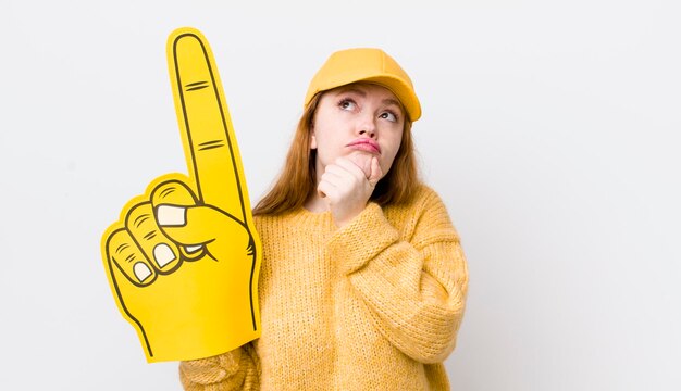 Mulher bonita ruiva pensando se sentindo duvidoso e confuso conceito de fã de mão número um