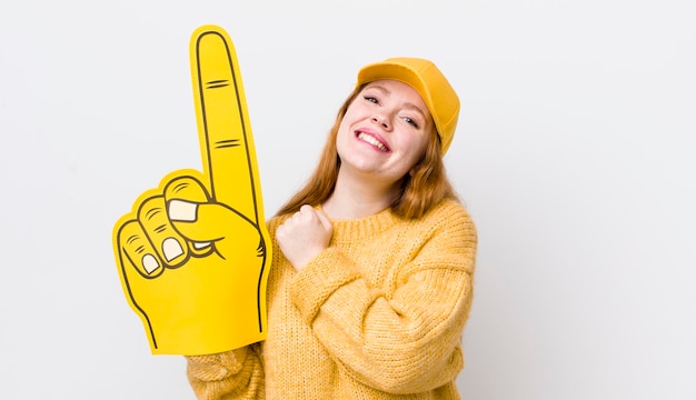 Mulher bonita ruiva se sentindo feliz e enfrentando um desafio ou celebrando o conceito de fã número um