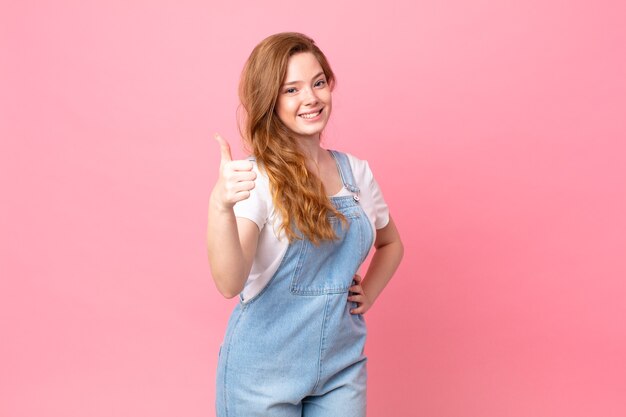 Mulher bonita ruiva se sentindo orgulhosa, sorrindo positivamente com o polegar para cima