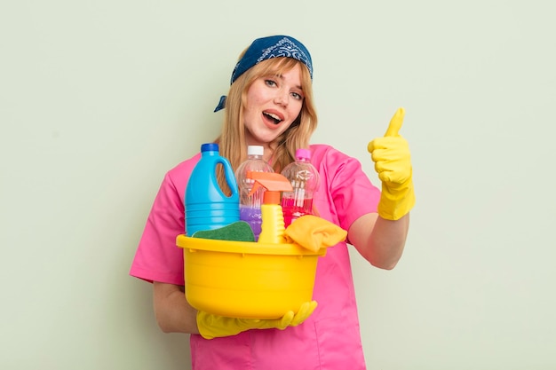 Mulher bonita ruiva se sentindo orgulhosa sorrindo positivamente com polegares para cima conceito de limpeza de limpeza