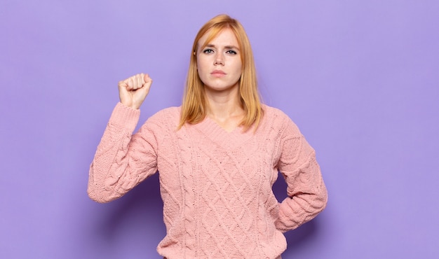 Mulher bonita ruiva se sentindo séria, forte e rebelde, levantando o punho, protestando ou lutando pela revolução