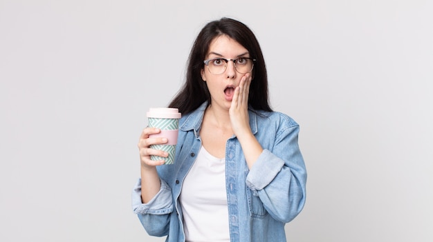 Mulher bonita se sentindo chocada e com medo e segurando um café para levar