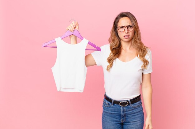 Mulher bonita se sentindo confusa e confusa e escolhendo roupas