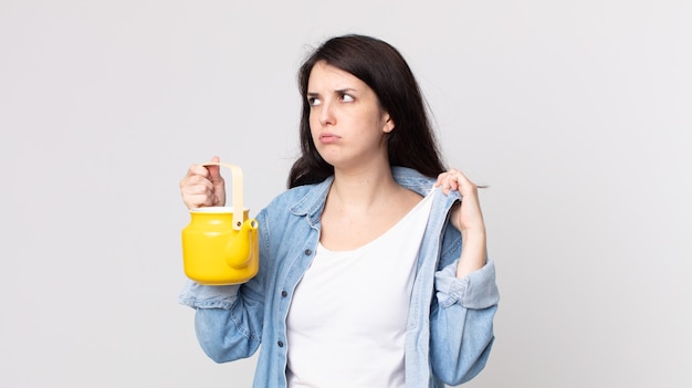 Mulher bonita se sentindo estressada, ansiosa, cansada e frustrada e segurando um bule de chá