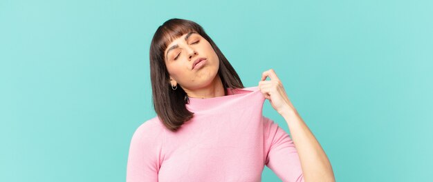 Mulher bonita se sentindo estressada, ansiosa, cansada e frustrada, puxando o pescoço da camisa, parecendo frustrada com o problema