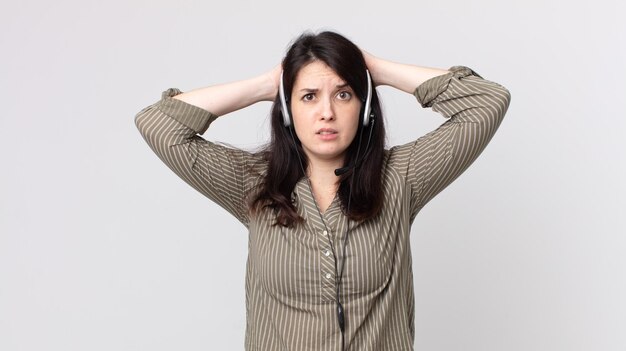 Mulher bonita se sentindo estressada, ansiosa ou com medo, com as mãos na cabeça. agente assistente com fone de ouvido