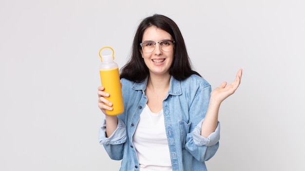 Mulher bonita se sentindo feliz e surpresa com algo inacreditável e segurando uma garrafa térmica de café