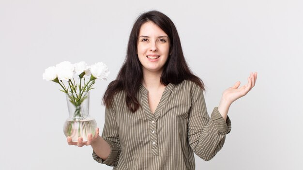 Mulher bonita se sentindo feliz, surpresa ao perceber uma solução ou ideia e segurando flores decorativas. agente assistente com fone de ouvido