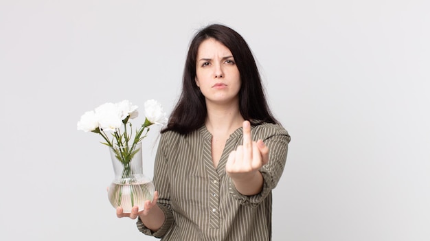 Mulher bonita se sentindo irritada, irritada, rebelde e agressiva e segurando flores decorativas. agente assistente com fone de ouvido