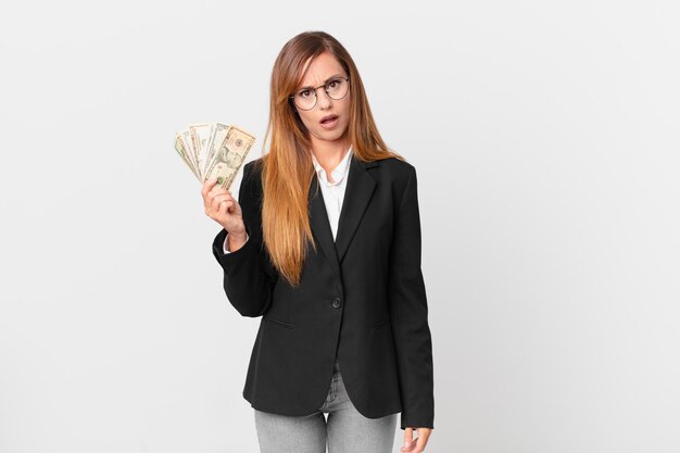 Mulher bonita se sentindo perplexa e confusa. conceito de negócios e dólares