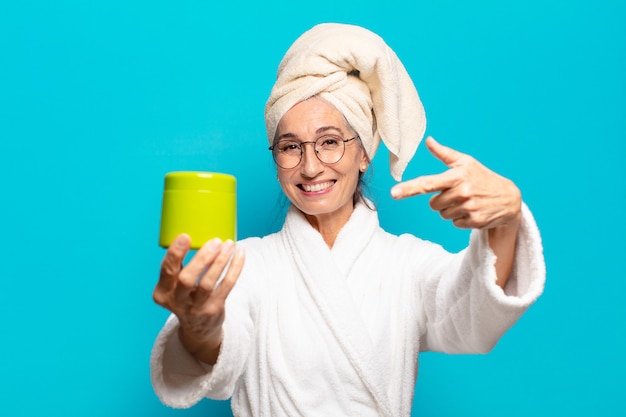 Mulher bonita sênior após o banho, vestindo um roupão de banho. conceito de produtos de limpeza ou banho facial