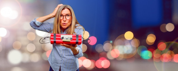 Mulher bonita sênior com uma bomba de dinamite