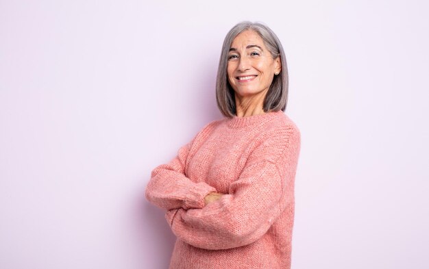 Mulher bonita sênior rindo alegremente com os braços cruzados, em uma pose relaxada, positiva e satisfeita