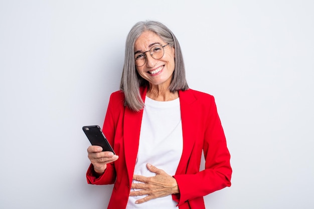 Mulher bonita sênior rindo alto de alguma piada hilária... conceito de negócios e telefone