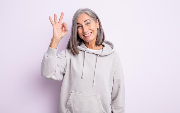 Mulher bonita sênior se sentindo feliz relaxada e satisfeita mostrando aprovação com gesto bem sorrindo