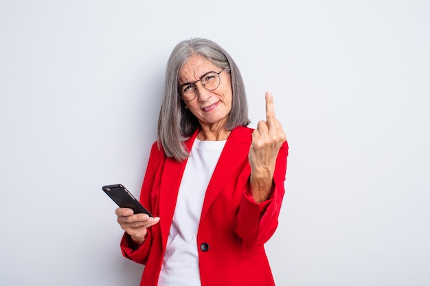 Mulher bonita sênior se sentindo zangada, irritada, rebelde e agressiva... conceito de negócios e telefone