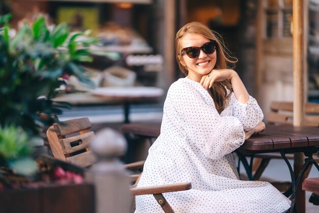 Mulher bonita sentada à mesa num café na rua da cidade Pessoas de moda, estilo de vida, conceito de viagem