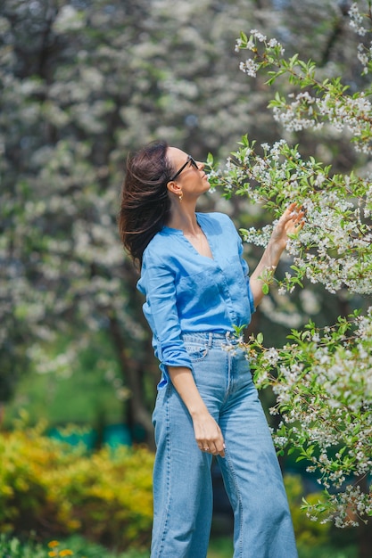 Mulher bonita sentindo o cheiro no jardim de cerejas da primavera