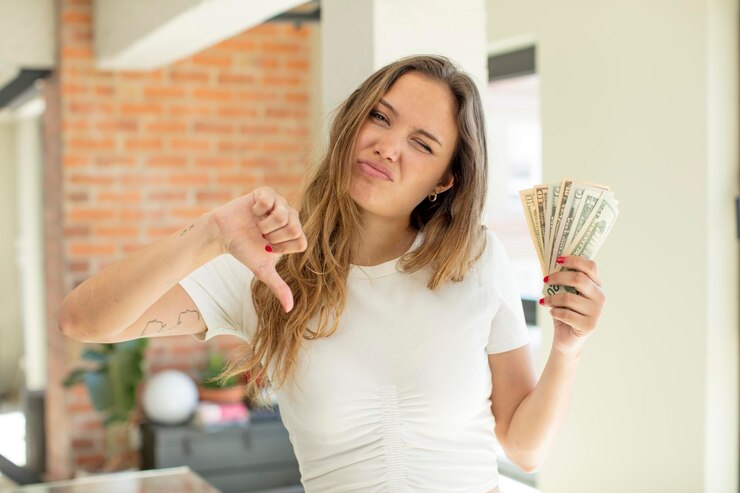 Foto mulher bonita, sentindo-se cruzando os polegares para baixo, conceito de notas de dólar