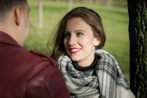 Mulher bonita sorridente, olhando para o namorado na frente dela no parque em um dia ensolarado. jovem casal apaixonado, aparência sensual de garota, flertando com o namorado, conceito de nervosismo no primeiro encontro