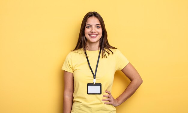 Mulher bonita sorrindo alegremente com uma mão no quadril e conceito de cartão de acreditação confiante