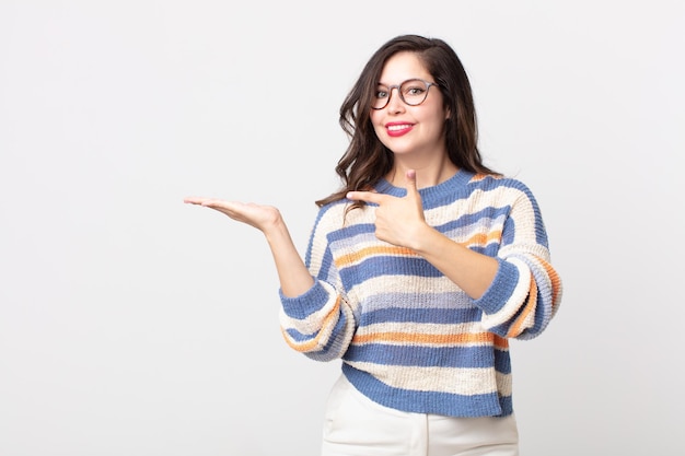 Mulher bonita sorrindo alegremente e apontando para copiar o espaço na palma da mão ao lado, mostrando ou anunciando um objeto