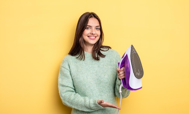 Mulher bonita sorrindo alegremente se sentindo feliz e mostrando um conceito de roupas de ferro conceito