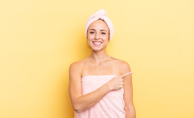 Mulher bonita sorrindo alegremente, sentindo-se feliz e apontando para o lado. conceito de chuveiro e beleza